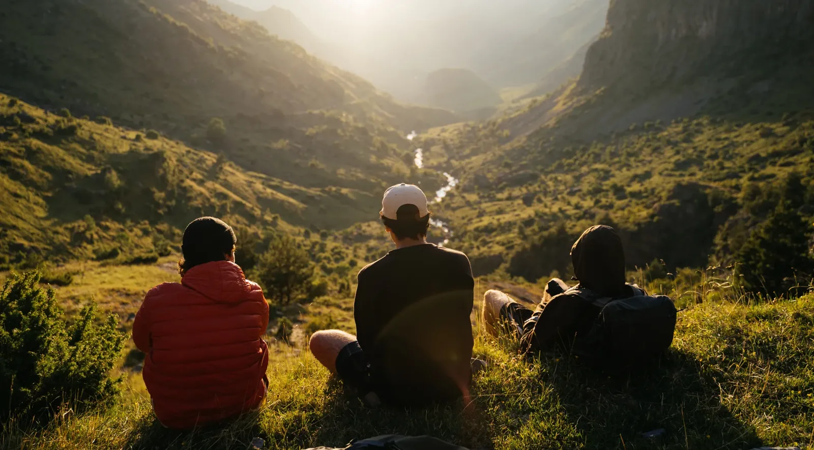 Trois randonneurs contemplent une vallée ensoleillée